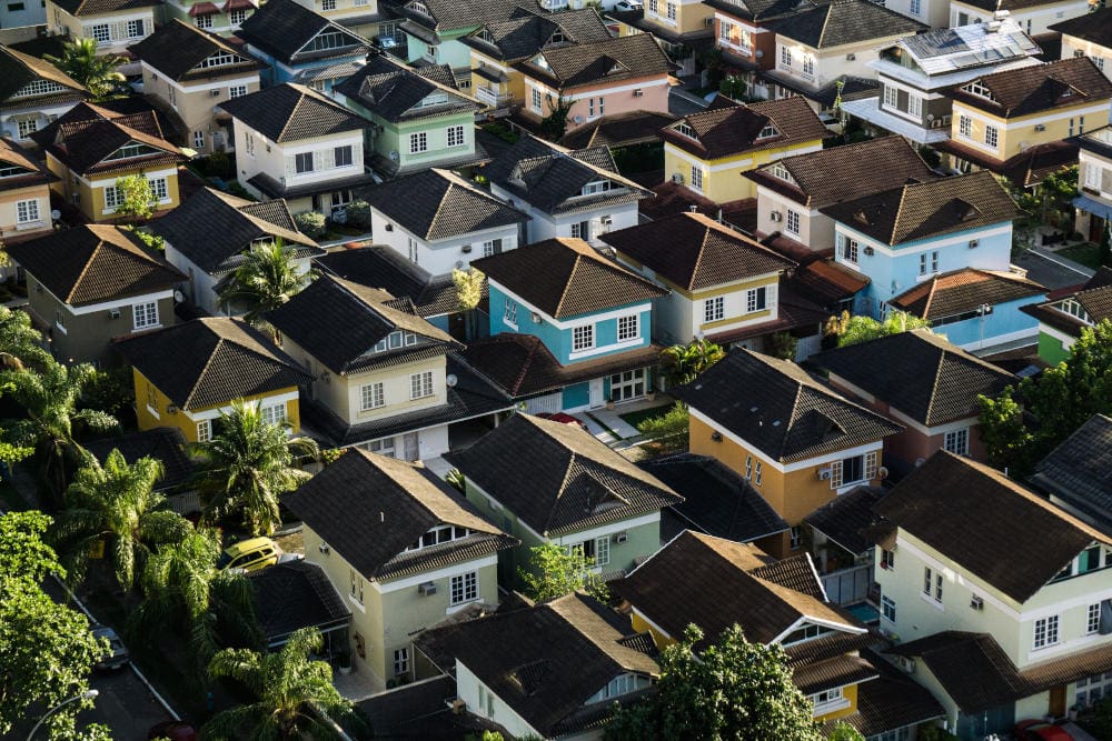 Aerial view of a densely packed neighborhood with colorful houses and dark roofs.