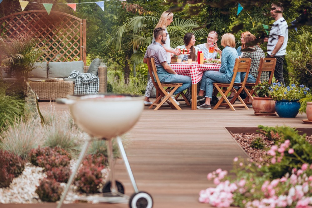 A group of people having a barbecue in a backyard.