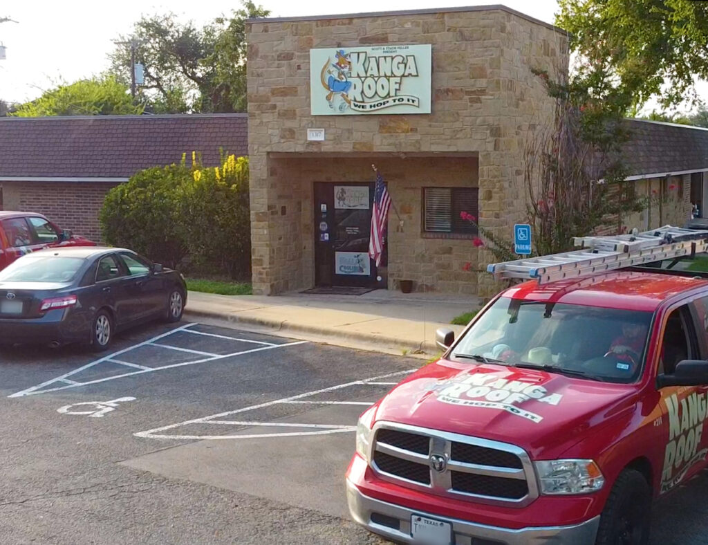 A brick building with a "Kanga Roof" sign; a red truck with the same logo is parked outside, along with other cars. An American flag is near the entrance.