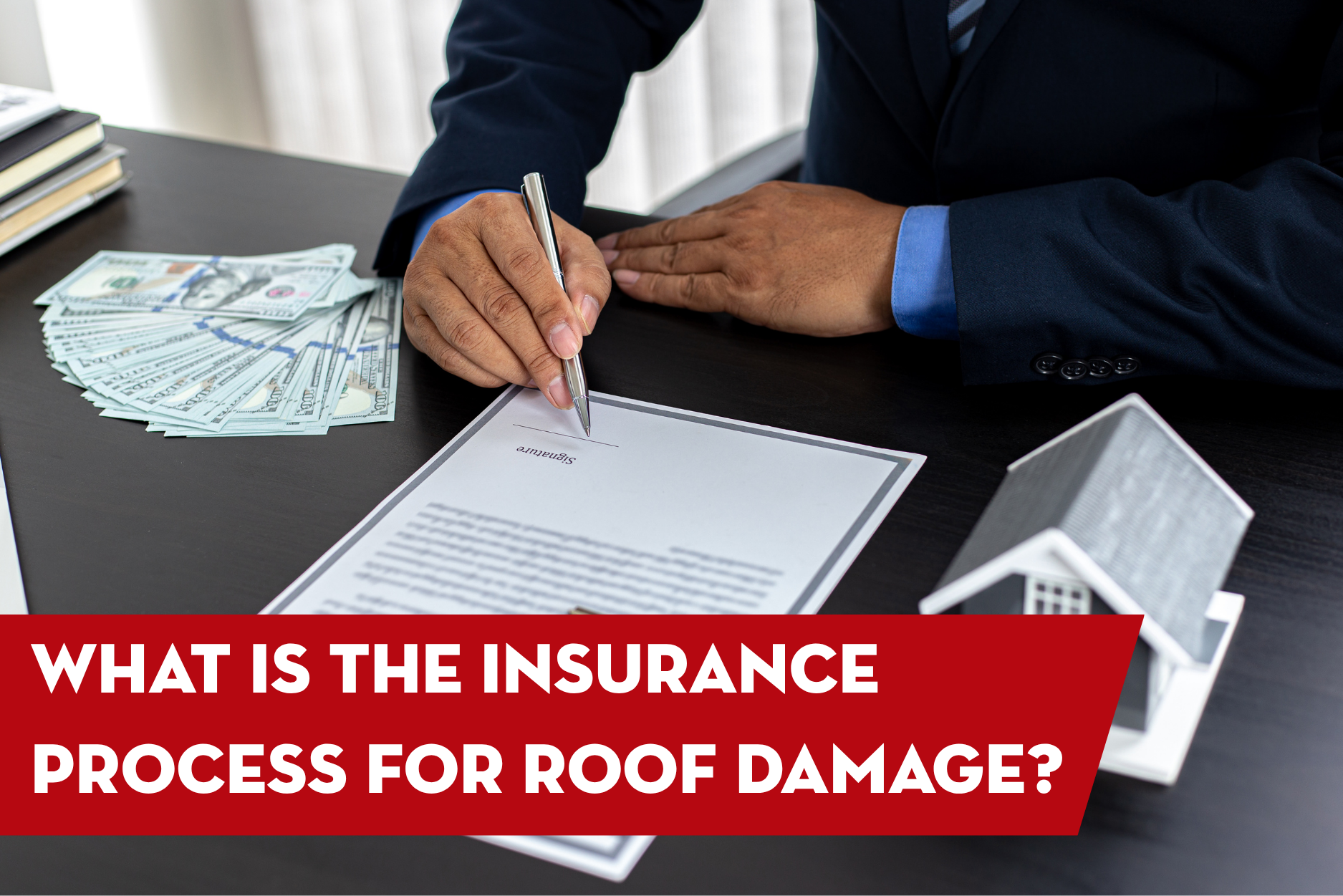Insurance representative reviewing and signing roof damage claim paperwork with cash and home model on desk during the insurance claims process